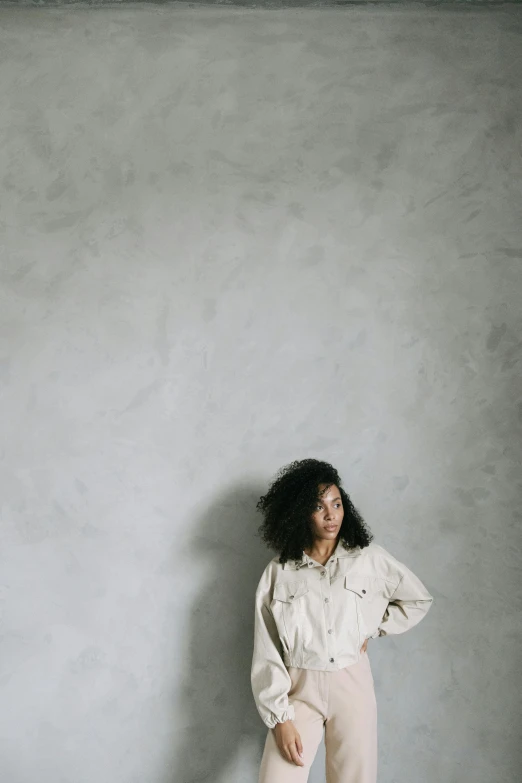 a woman standing in front of a white wall, by Pablo Rey, curly haired, gongbi, gray skin. grunge, wearing a linen shirt