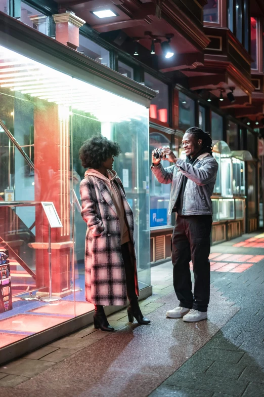 a couple of people standing in front of a store window, pexels contest winner, happening, film lighting, seoul, taking a picture, jamel shabazz