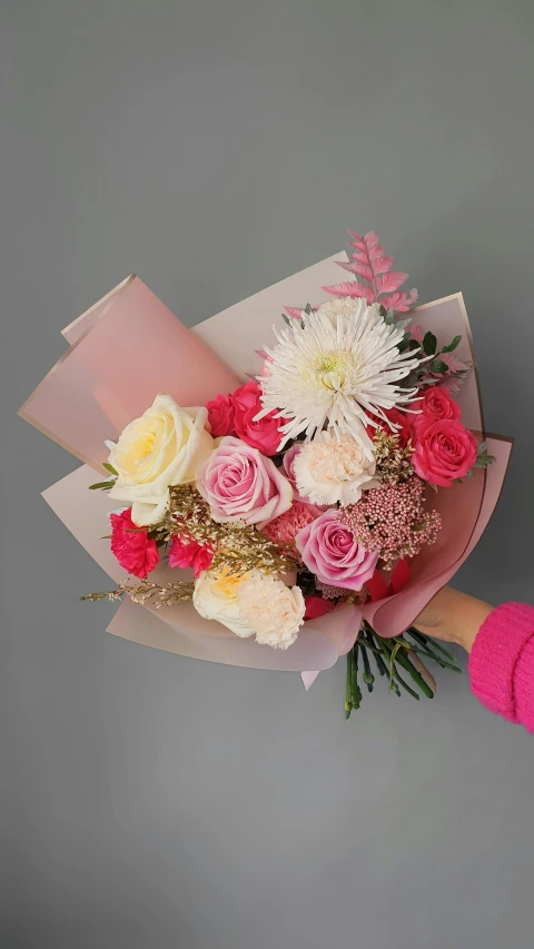 a woman holding a bouquet of pink and white flowers, pink and gold color scheme, on grey background