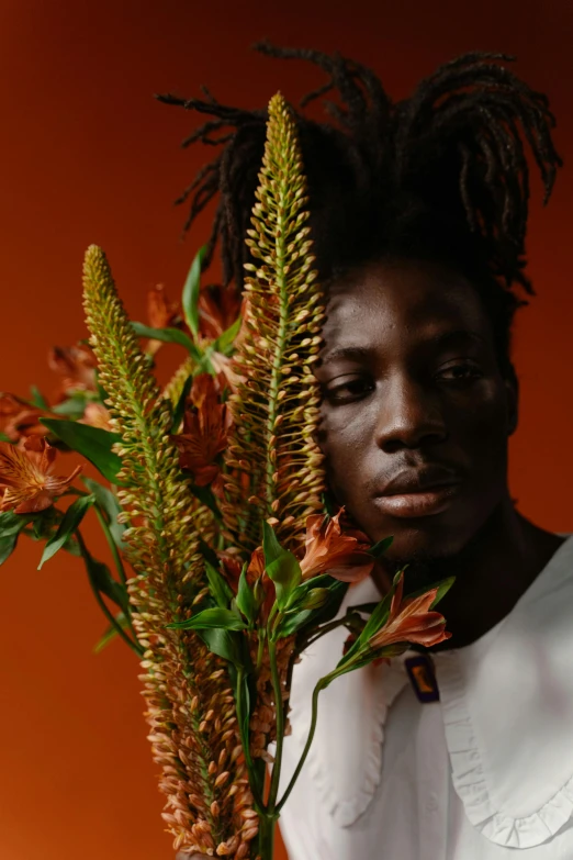 a woman with dreadlocks holding a bouquet of flowers, inspired by Ras Akyem, trending on unsplash, afrofuturism, young man, orange tone, next to a plant, mapplethorpe