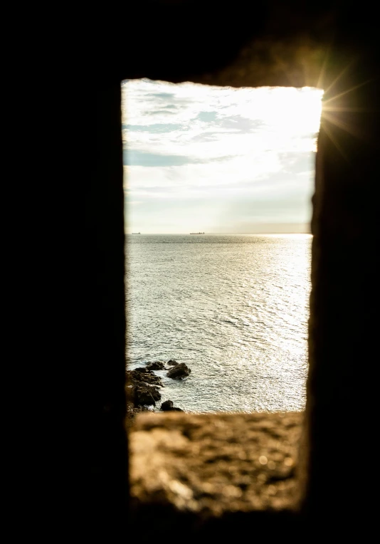 a view of the ocean through a window, by Tobias Stimmer, unsplash, epic vista of old ruins, evening sunlight, slide show, natural prison light