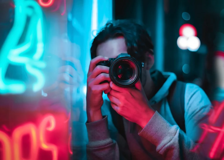 a man taking a picture with a camera, unsplash contest winner, art photography, with neon lights, staring at viewer, telephoto, cinematic light and reflections