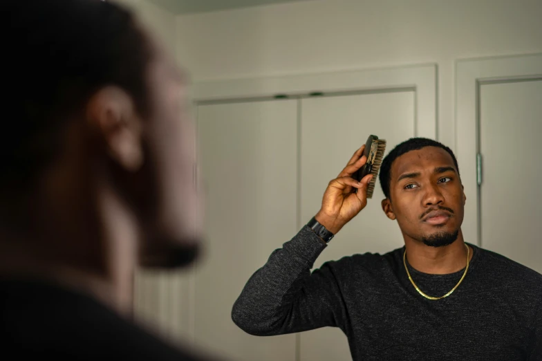 a man brushing his hair in front of a mirror, by Everett Warner, pexels contest winner, realism, ( ( dark skin ) ), square masculine jaw, he is about 20 years old | short, captured on canon eos r 6