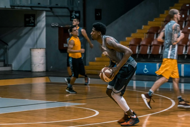 a group of young men playing a game of basketball, dribble, grey orange, liam brazier, focused photo, looking to his side