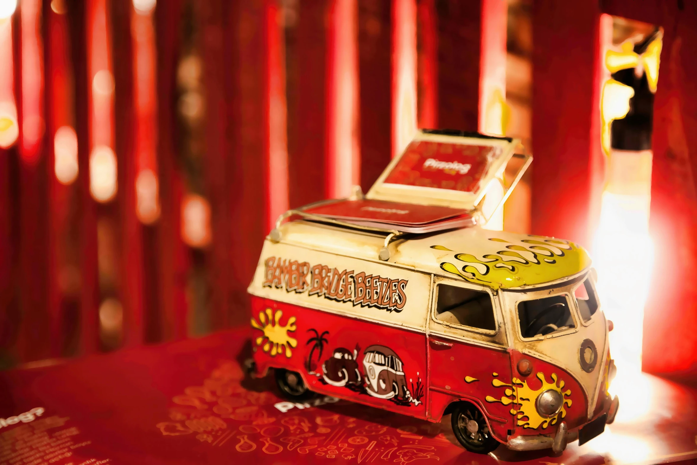a toy van sitting on top of a table, graffiti, crimson themed, vintage showcase of the 60s, chinese heritage, food