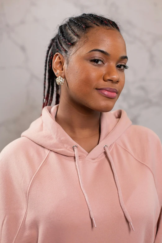 a woman in a pink hoodie poses for a picture, trending on pexels, renaissance, long cornrows, solid background, detailed product image, light brown skin!