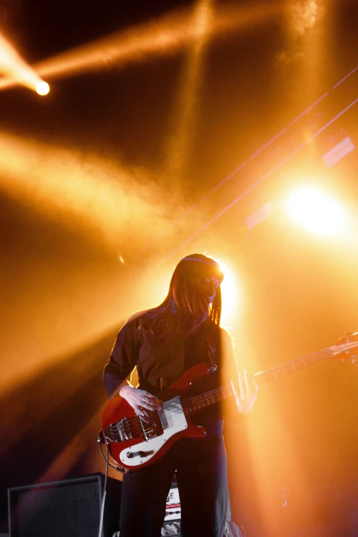 a man that is playing a guitar on a stage, pexels contest winner, light and space, with red haze, crystal castles, in 2 0 1 2, buckethead