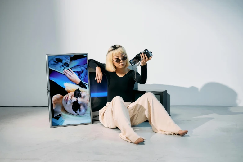 a woman taking a picture of herself with a camera, an album cover, video art, light box, kda and sam yang, futuristic clothing, laying down