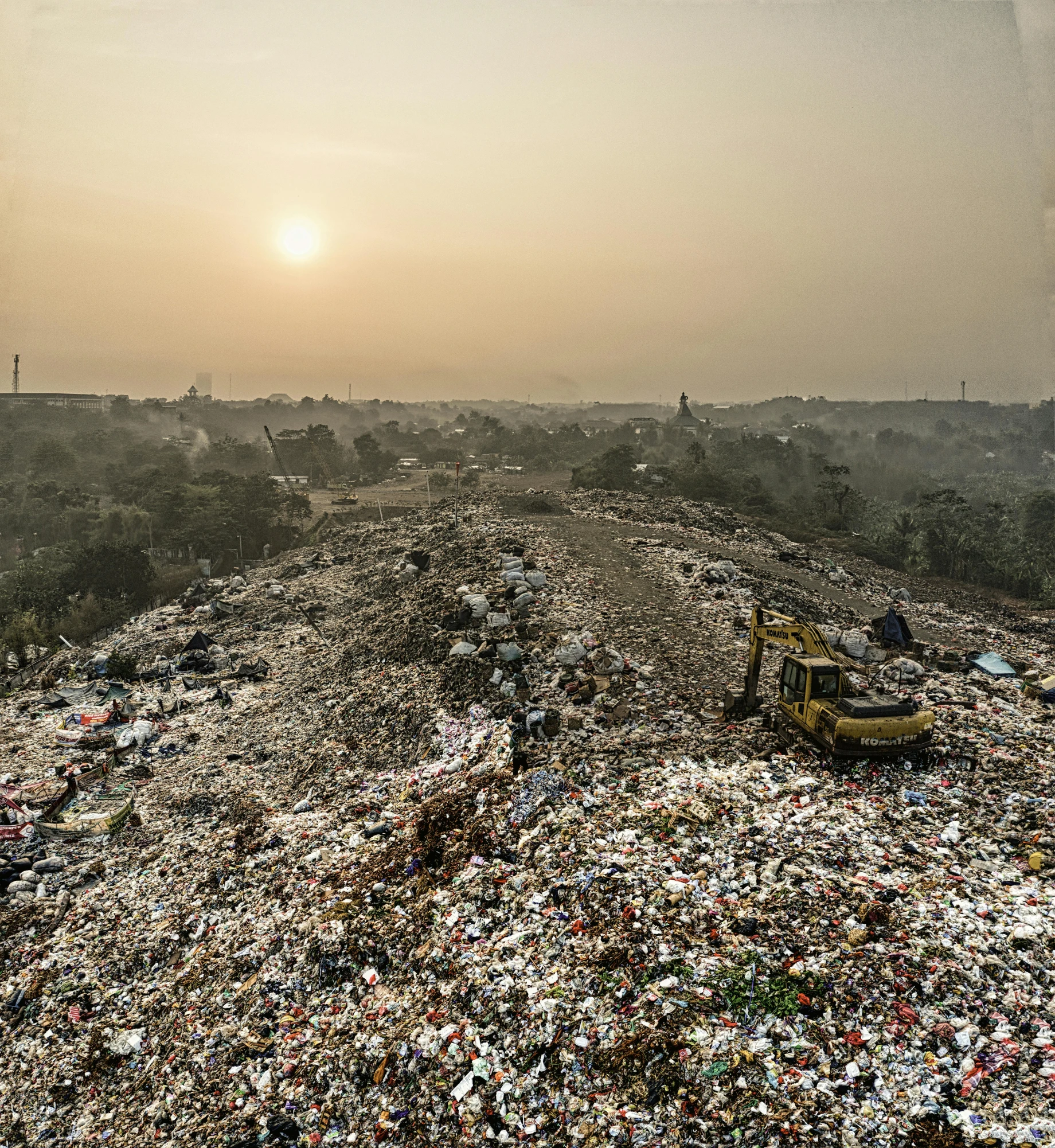 a bulldozer sitting on top of a pile of garbage, by Daniel Lieske, unsplash, happening, sun at dawn, wide landscape, kris kuksi, jakarta