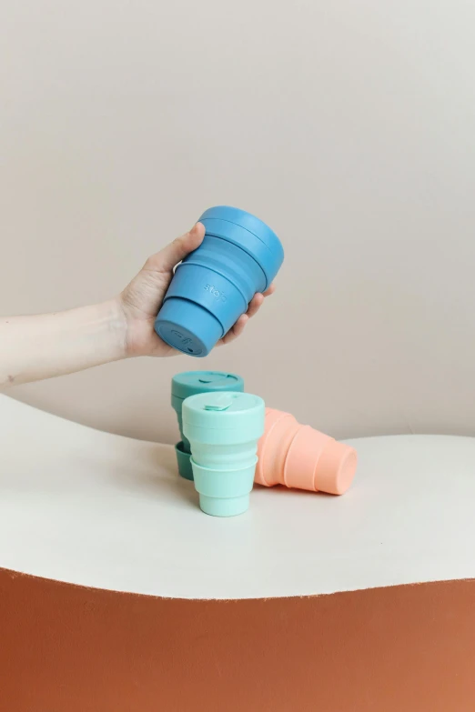 a person holding a cup on top of a table, product image, silicone skin, folded, thumbnail