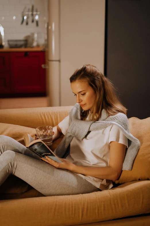 a woman sitting on a couch reading a book, by Adam Marczyński, pexels contest winner, happening, advanced technology, casually dressed, gif, summer evening