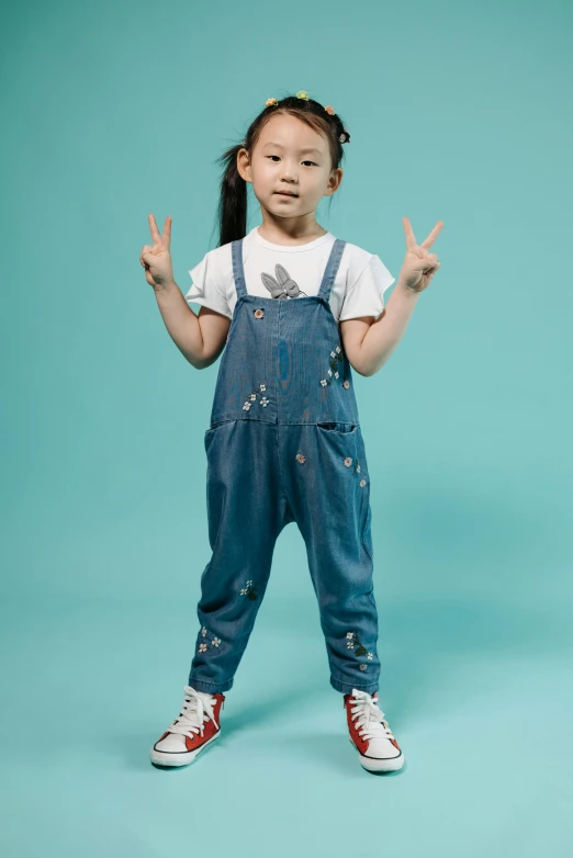 a little girl making a peace sign with her hands, by disney, unsplash, painted overalls, full height view, gongbi, official product photo