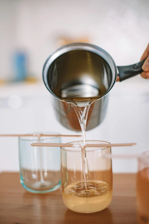 a person pouring a liquid into a glass, unsplash, wood cups, gelatine silver process, perfectly centered, at home