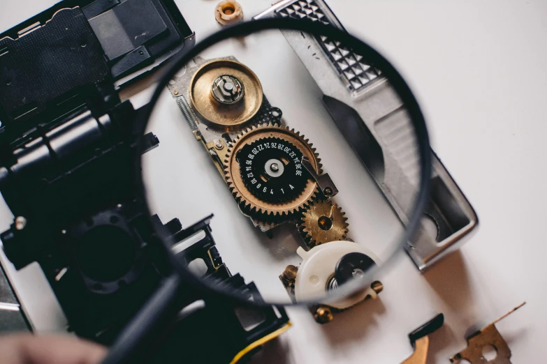 a close up of a person holding a magnifying glass, unsplash, assemblage, cogs and wheels, computer equipment, hasselblad photo