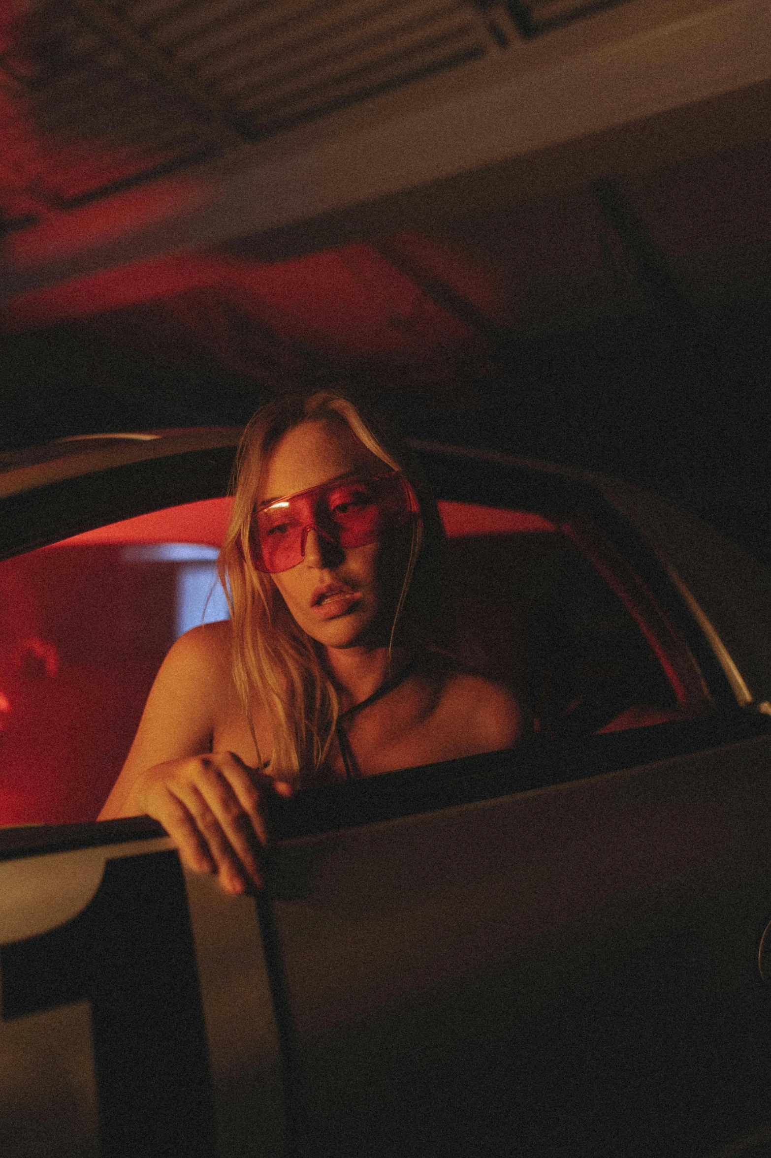 a woman sitting in the passenger seat of a car, inspired by Nan Goldin, trending on pexels, red door blonde, neon lenses, ( ( theatrical ) ), sydney sweeney