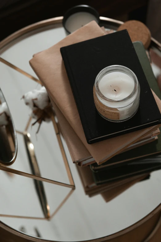 a glass table topped with books and a candle, trending on pexels, close-up from above, mixed materials, detailed product image, ignant