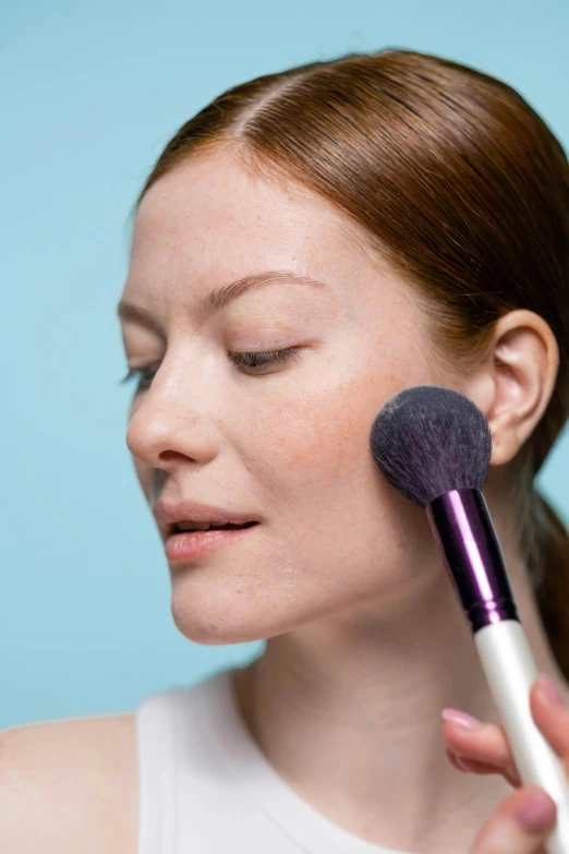 a woman brushes her face with a makeup brush, a stipple, opalescent mist, portrait of sanna marin, angled, how-to