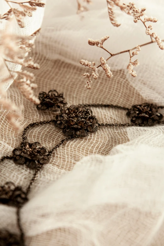 a bunch of flowers sitting on top of a table, inspired by Jules Robert Auguste, unsplash, rococo, metal lace, black jewellery, muted brown, detailed product image