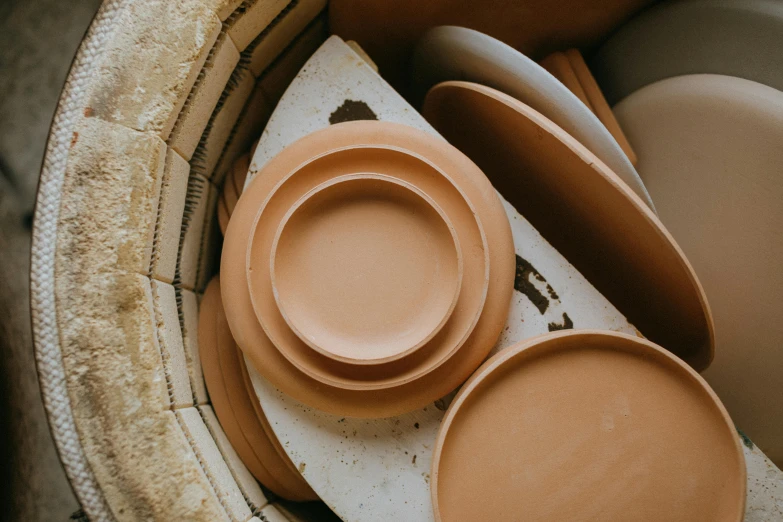 a bowl filled with plates and bowls sitting on top of a table, a still life, by Jessie Algie, trending on pexels, plasticien, terracotta, sandstone, close-up product photo, full pallet image