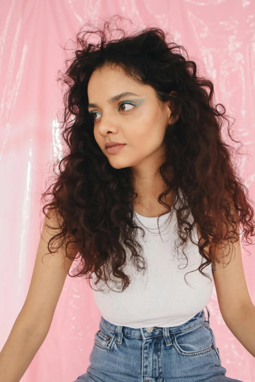 a beautiful young woman sitting on top of a bed, an album cover, featured on instagram, renaissance, long wild black curly hair, at a fashion shoot, teal studio backdrop, loosely cropped