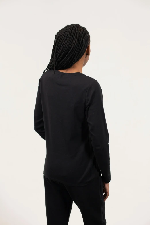 a woman standing in front of a white wall, inspired by Hendrick Goudt, unsplash, long sleeve, back view. nuri iyem, casual black clothing, panel of black