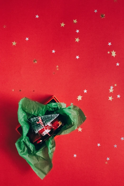 a green wrapper sitting on top of a red surface, pexels contest winner, tiny stars, wine, presents, gif