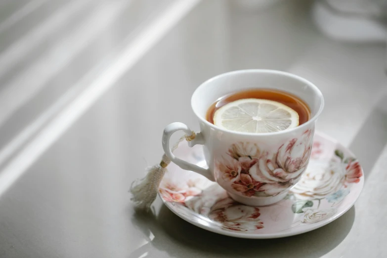 a cup of tea sitting on top of a saucer, inspired by Richmond Barthé, trending on pexels, lemon, white and pink cloth, round-cropped, immaculately detailed