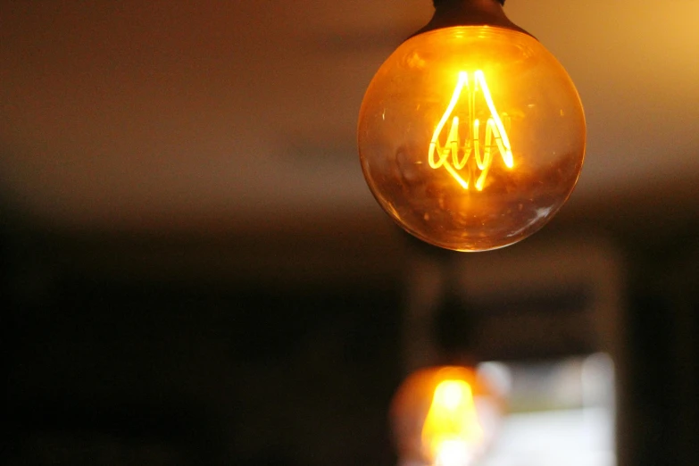 a close up of a light bulb hanging from a ceiling, by David Simpson, pexels, orange neon backlighting, cafe lighting, electric wallpaper, yellow lighting from right