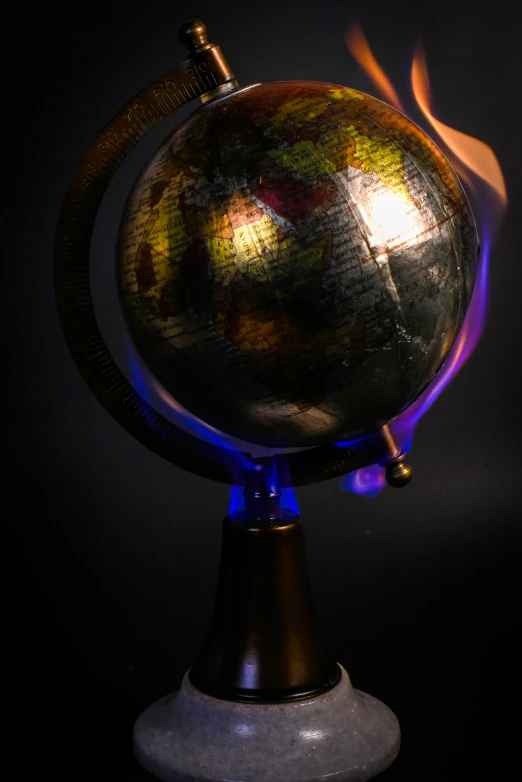 a burning globe sitting on top of a table, by Greg Rutkowski, kinetic art, vivid studio light, taken in the early 2020s, medium close-up shot, atmospheric lighting - n 9