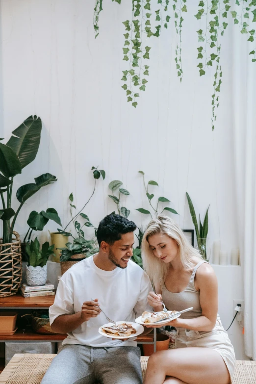 a man and a woman sitting at a table eating pizza, by Cosmo Alexander, pexels contest winner, room full of plants, in a white boho style studio, gif, romantic lead