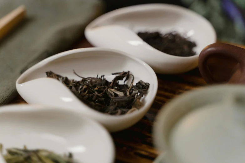 a table topped with bowls filled with different types of tea, inspired by Gu An, trending on unsplash, process art, white, close up portrait shot, ivory and ebony, digital image