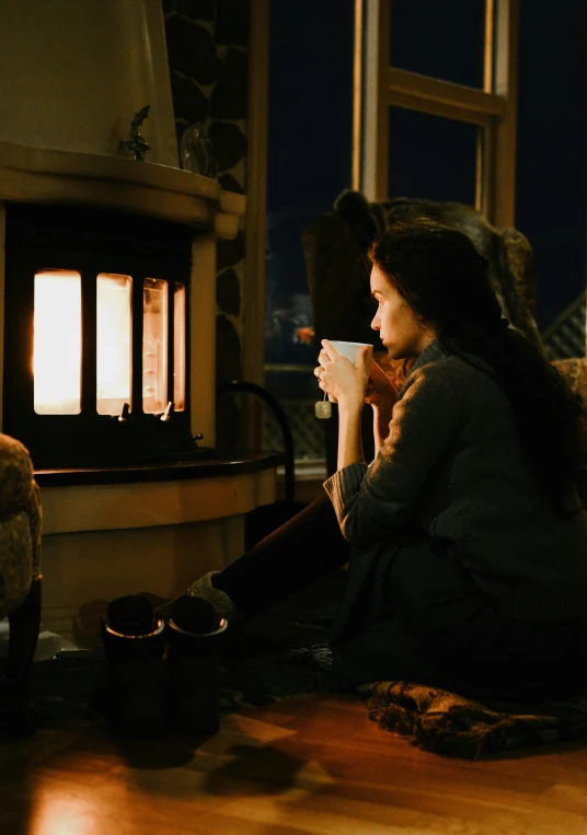 a woman sitting on the floor in front of a fire place, profile image, cold freezing nights, morning coffee, cinematic movie still