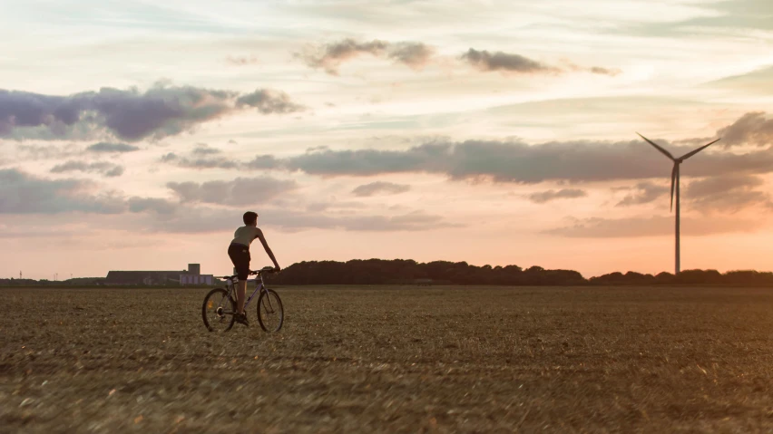 a person riding a bike in a field, pexels contest winner, late summer evening, northern france, wide film still, skies