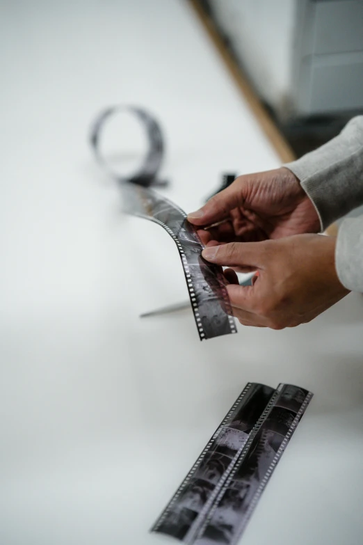 a person cutting a piece of paper with a pair of scissors, unsplash, video art, film strip reel showing 9 frames, tailored clothing, in a workshop, high quality photo