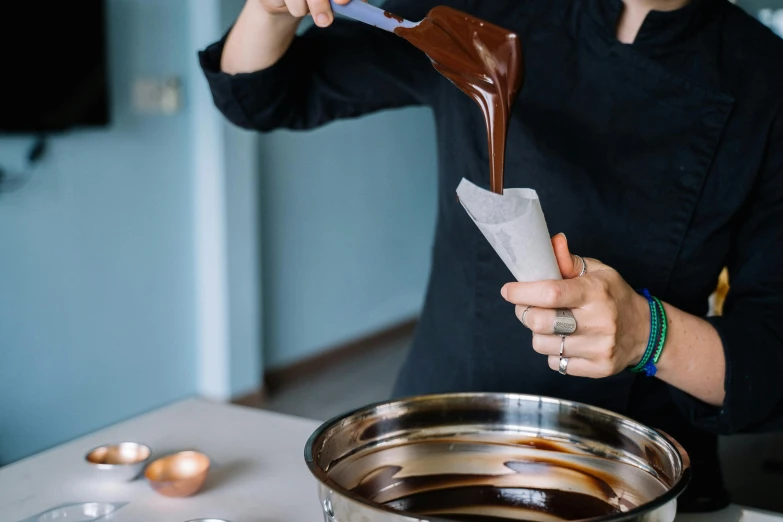 a woman is pouring chocolate into a pot, pexels contest winner, jen atkin, holding an epée, smooth contours, foil