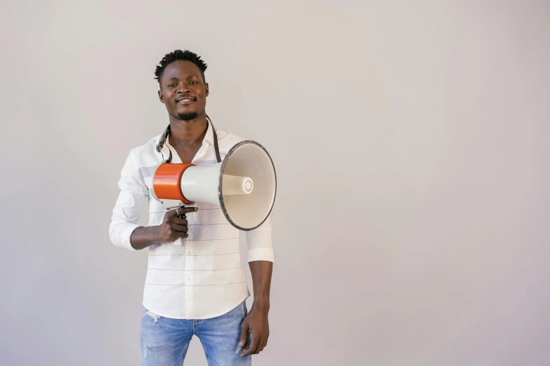 a man with a megaphone in his hand, by Amos Ferguson, pexels contest winner, afrofuturism, healthcare worker, handsome male, plain background, instagram picture