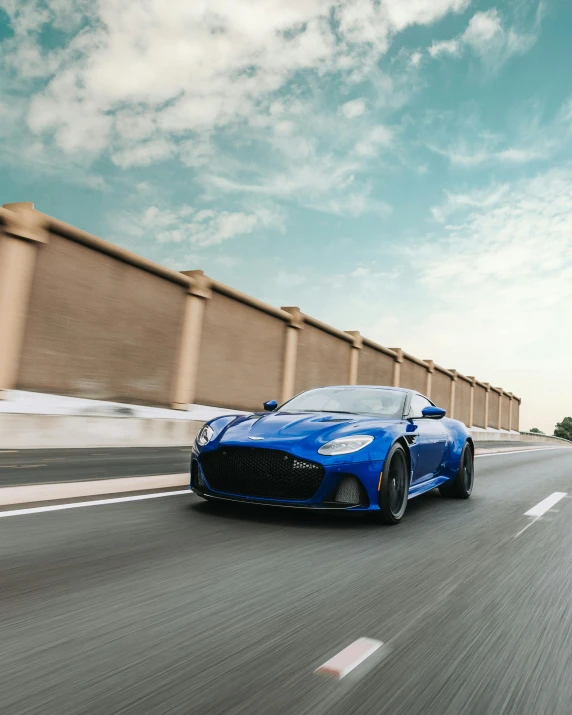 a blue sports car driving down a highway, inspired by Harry Haenigsen, pexels contest winner, renaissance, aston martin, avatar image, square, ultra wide horizon