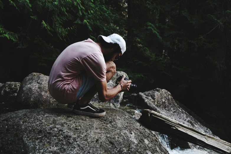 a man kneeling on top of a rock next to a river, pexels contest winner, peacefully drinking river water, instagram photo shoot, forest picnic, looking down on the camera