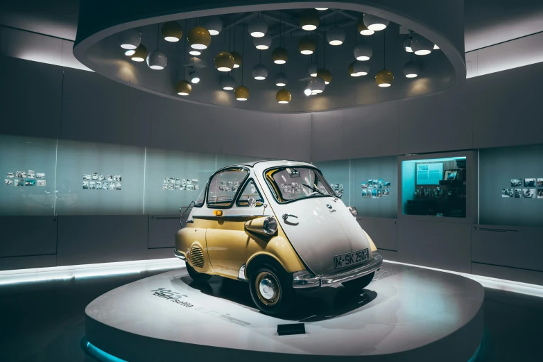 a small car is on display in a museum, by Matthias Stom, trending on unsplash, retrofuturism, an film still of mr bean, exhibition hall lighting, silver and yellow color scheme, kama russian electrocar