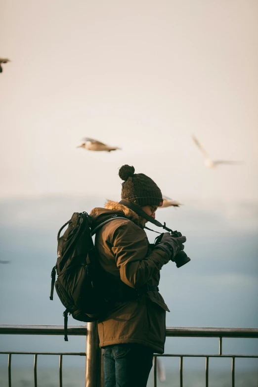 a man with a backpack taking a picture of seagulls, by Jan Tengnagel, happening, wearing adventuring gear, telephoto vacation picture, plane, candid portrait photo