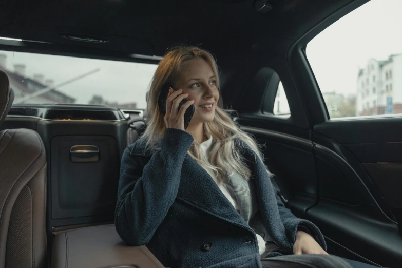 a woman sitting in the back seat of a car talking on a cell phone, by Emma Andijewska, happening, **cinematic, blonde, high class, high quality upload