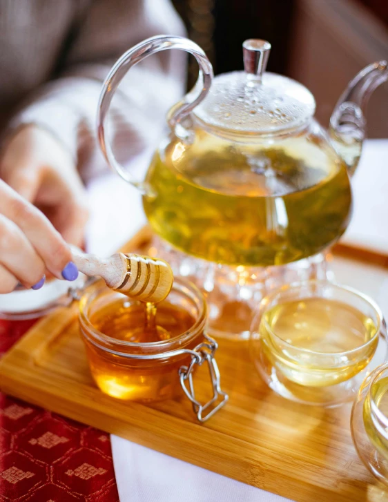 a tea pot sitting on top of a wooden tray, by Julia Pishtar, trending on pexels, jar of honey, eating, square, skincare