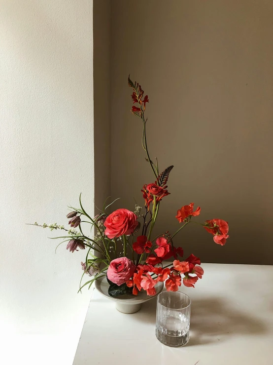 a vase filled with red flowers sitting on a table, by Jessie Algie, featured on pinterest, overgrown with puffy orchids, modern minimalist f 2 0, small red roses, with a soft