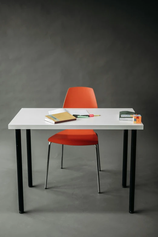 a desk with a chair and a book on it, sitting on a table, on a gray background, black steel with red trim, studio orange