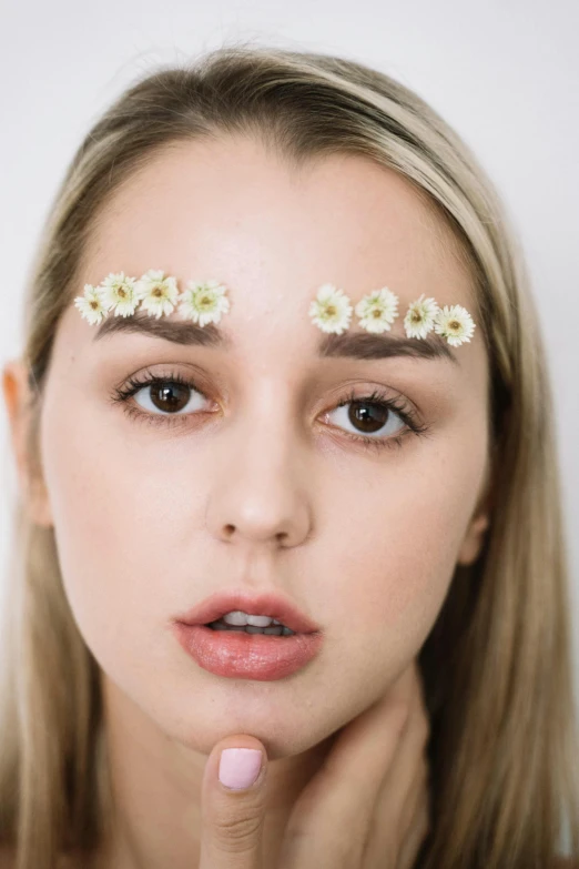 a woman with daisies on her forehead, an album cover, inspired by Elsa Bleda, trending on pexels, big eyebrows, sydney sweeney, detail shot, clear symmetrical face