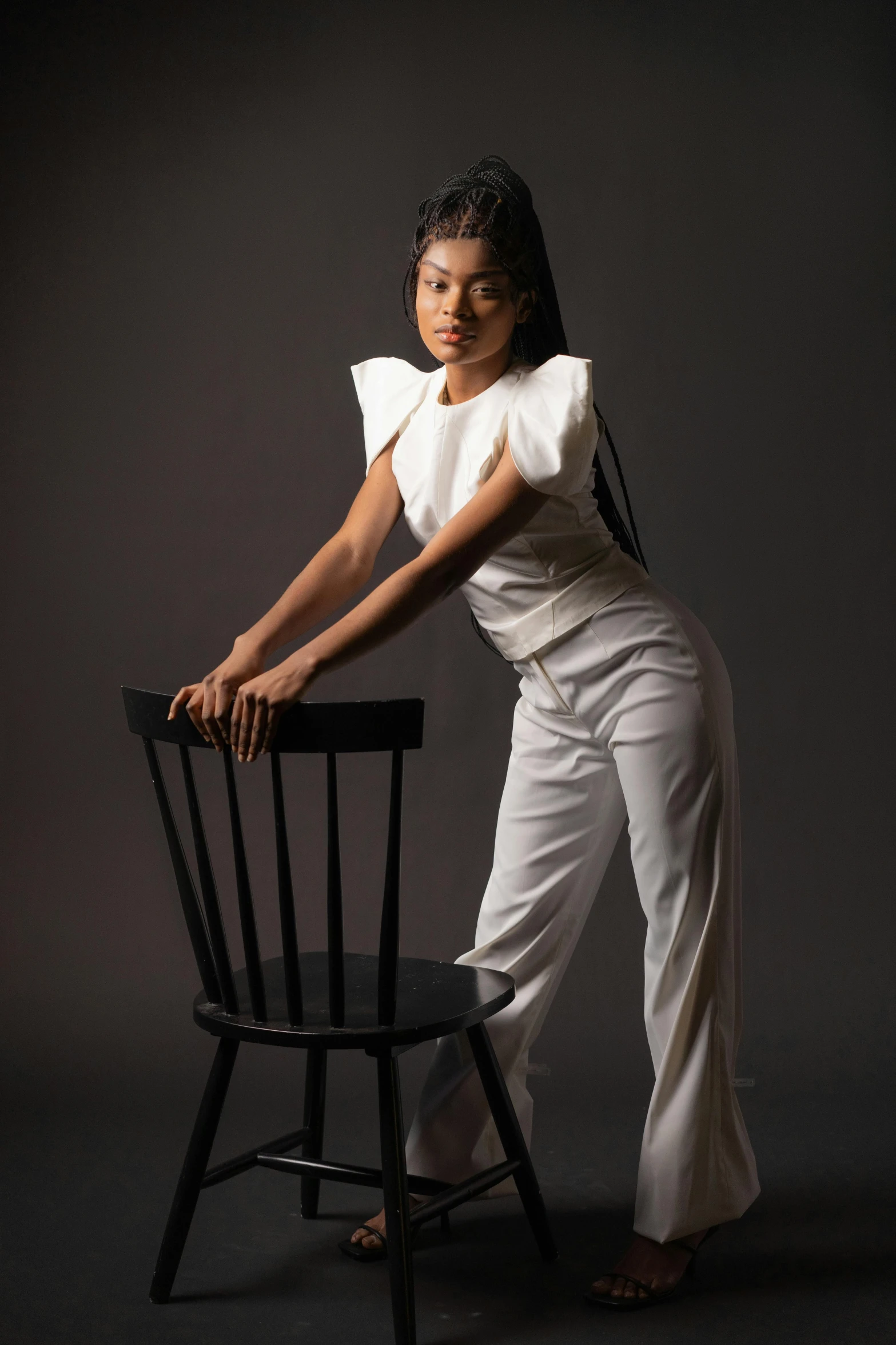 a woman sitting on top of a wooden chair, a portrait, by Lily Delissa Joseph, pexels contest winner, white outfit, zendaya, battle pose, standing