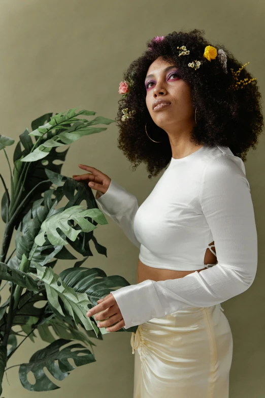 a woman standing next to a potted plant, an album cover, pexels contest winner, renaissance, wearing a crop top, white outfit, curls, designed for cozy aesthetics!