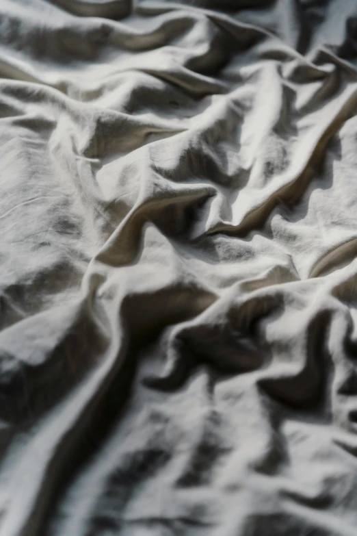 a close up of a blanket on a bed, inspired by Anna Füssli, trending on unsplash, paper crumpled texture, in volumetric soft glowing mist, grey metal body, clay material