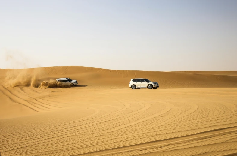 a couple of cars that are in the sand, dau-al-set, in a vast serene landscape, falling sand inside, hunting