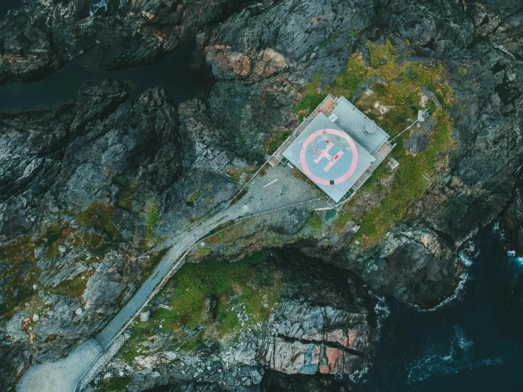 a house sitting on top of a cliff next to a body of water, by Jesper Knudsen, pexels contest winner, graffiti, helicopter view, gigantic landing pad, 2 5 6 x 2 5 6 pixels, a road leading to the lighthouse